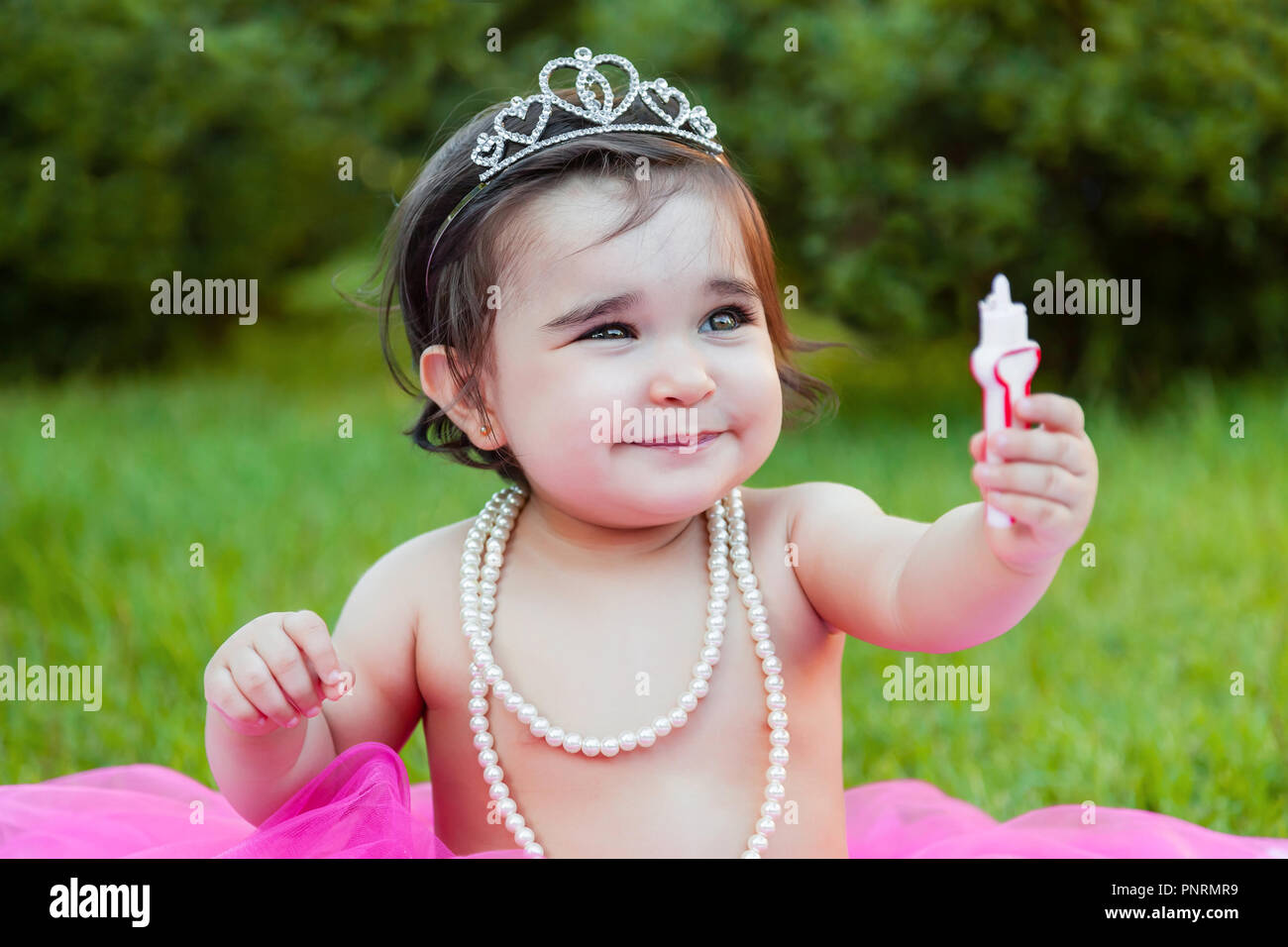 Baby toddler girl primo compleanno festa anniversario, giocando con candela, faccia sporca e facendo un pasticcio di torta rosa con candela. Princess costume Foto Stock