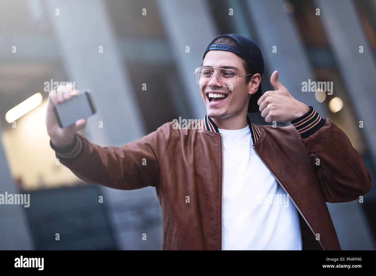 Selfie mania! Eccitato giovane ragazzo sta facendo selfie su una telecamera. Egli indossa casual usura alla moda e ritornano a scatto Foto Stock