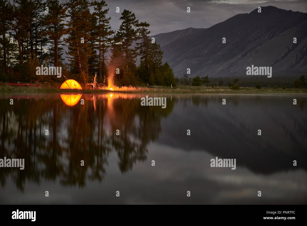 Tenda arancione sulla costa del lago di notte. Foto Stock