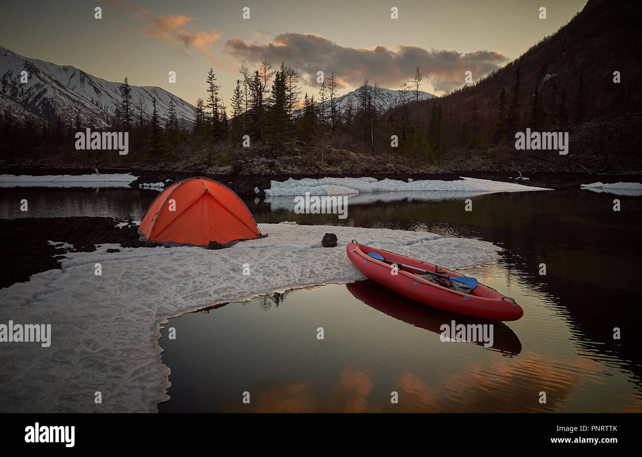 Campeggio con tenda arancione e canoa sul lago Foto Stock