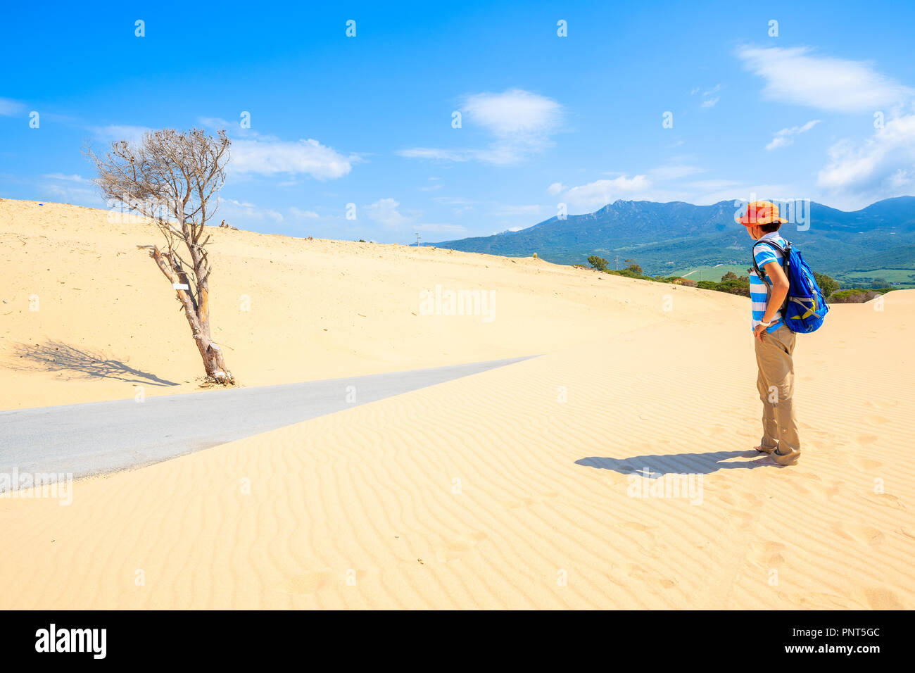 Giovane donna tourist permanente sulla duna di sabbia e guardando al desert road vicino al Paloma Beach, Andalusia, Spagna Foto Stock