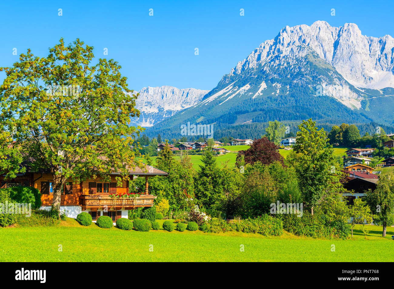 Casa Tradizionale su prato verde a Going am Wilden Kaiser mountain village, Alpi Kitzbühel, Austria Foto Stock