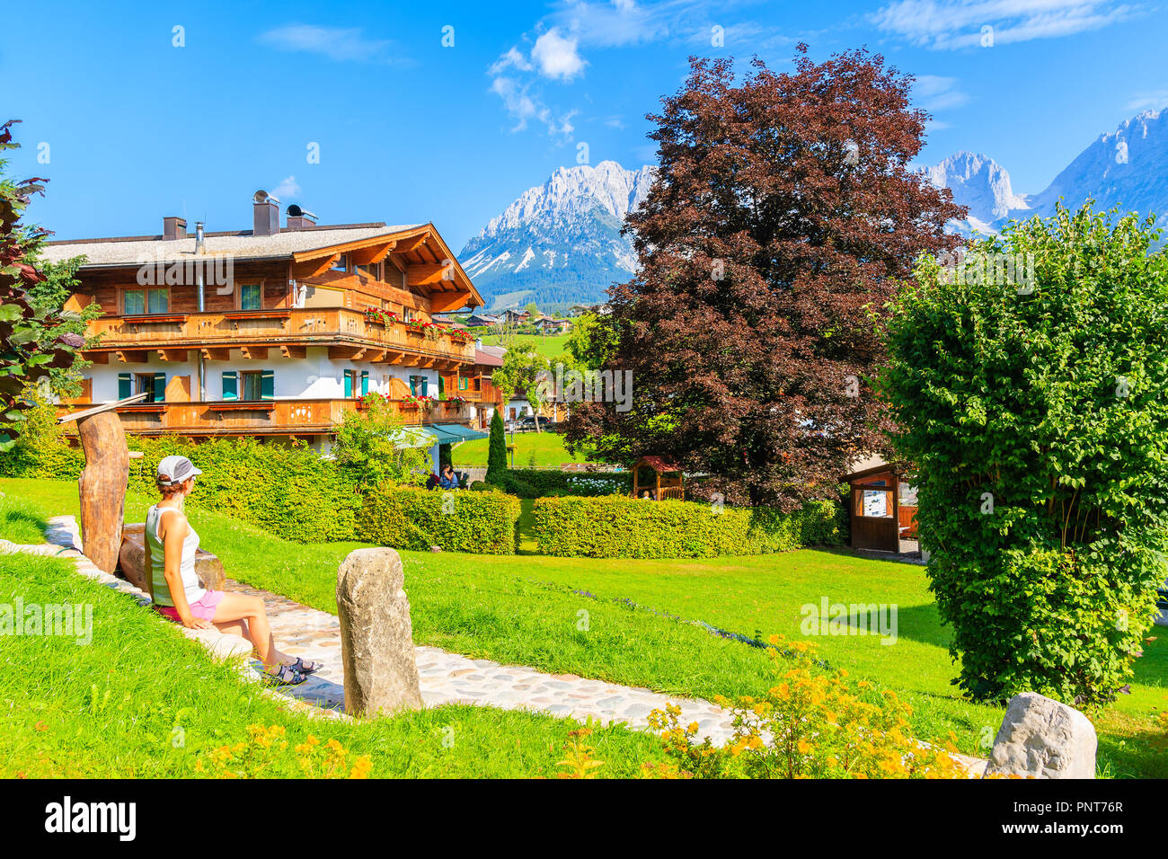 In legno tipico casa alpina contro Alpi montagne sullo sfondo verde prato a Going am Wilden Kaiser villaggio sulla soleggiata giornata estiva, Tirolo, Austria Foto Stock