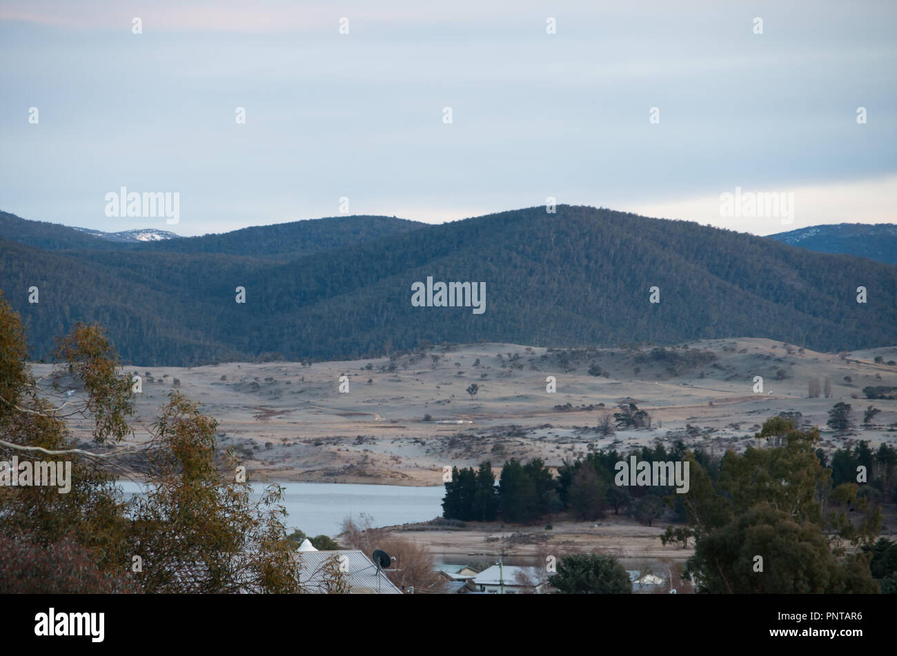 Affacciato sul lago jindabyne e sulle montagne innevate su una mattina ancora Foto Stock