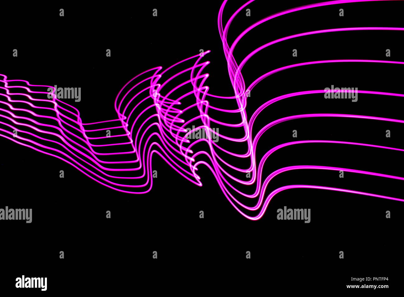 Luce fotografia pittura, una lunga esposizione foto di rosa le luci fairy in una striatura astratta del pattern luminoso contro uno sfondo nero Foto Stock