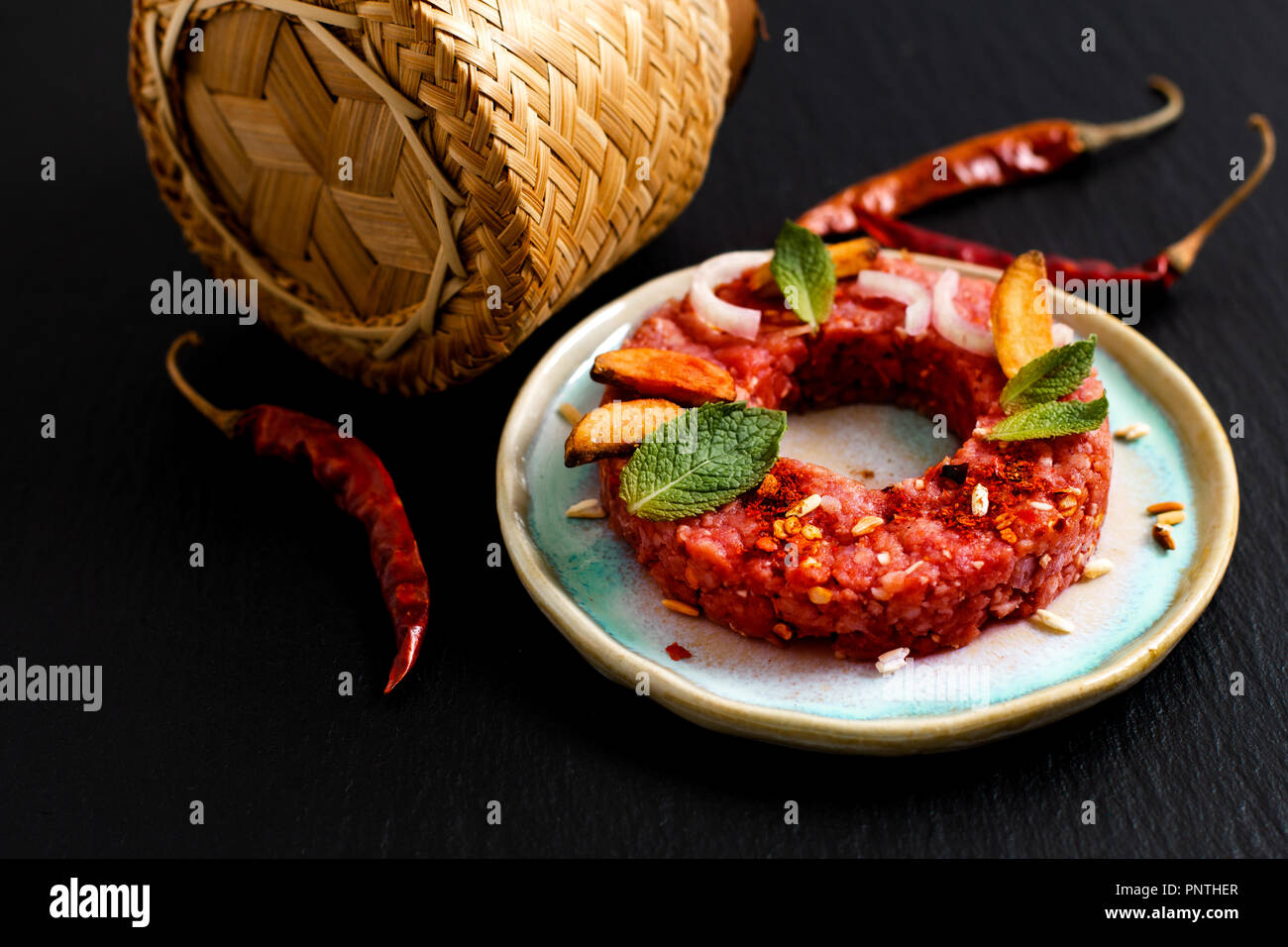 Concetto di cibo crudo speziato Larb Thai, Tartara di manzo stile tailandese sul nero ardesia scheda con spazio di copia Foto Stock