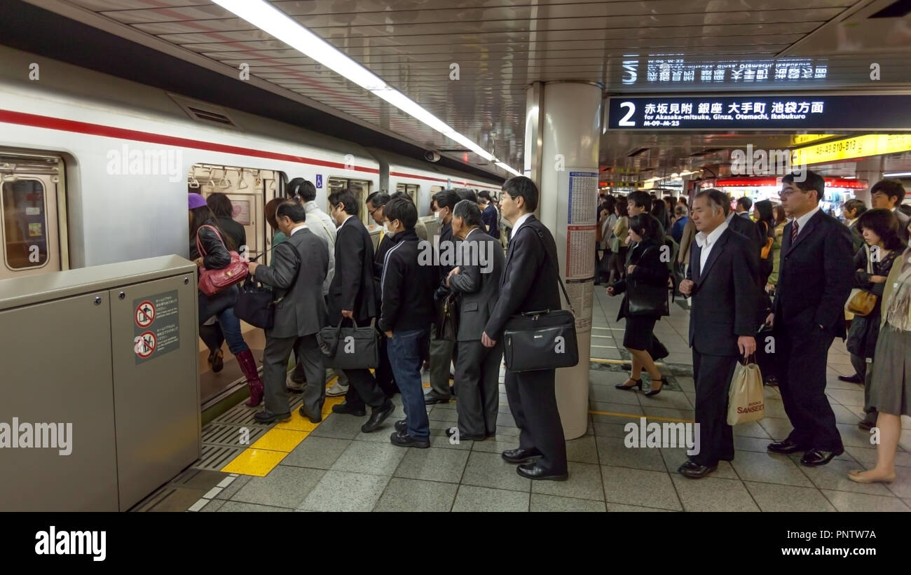 Pendolari giapponese di salire a bordo del treno della metropolitana di Tokyo, Giappone Foto Stock