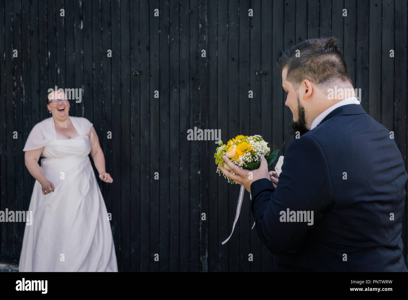 Il marito le catture il bouquet della sposa Foto Stock