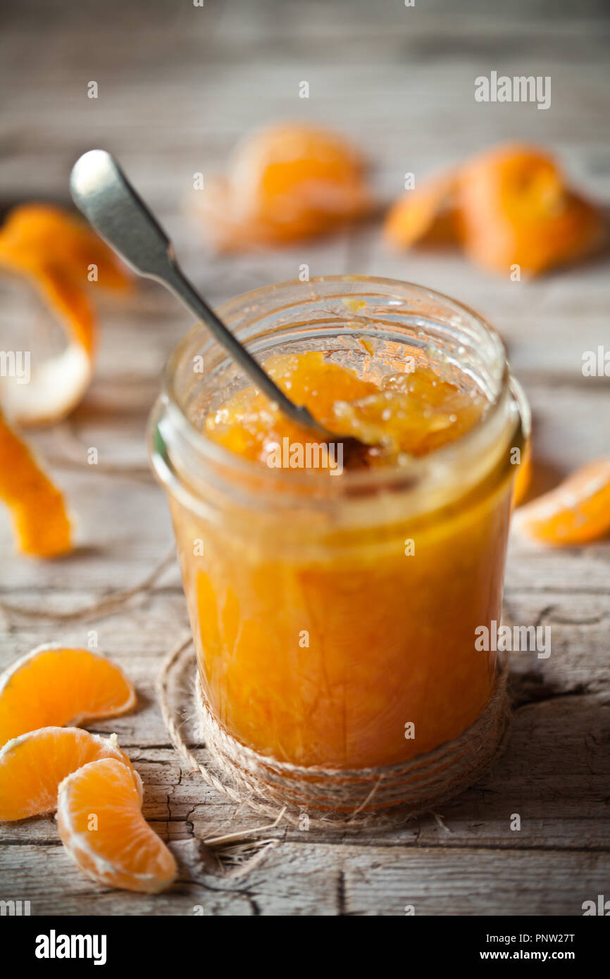 Tangerine inceppamento in un vasetto di vetro sul rustico sfondo di legno Foto Stock