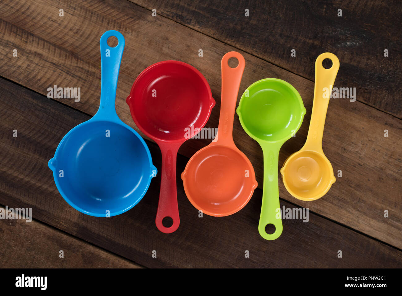 Colorate tazze di misurazione su un tavolo di legno. Utensili da cucina di concetto Foto Stock