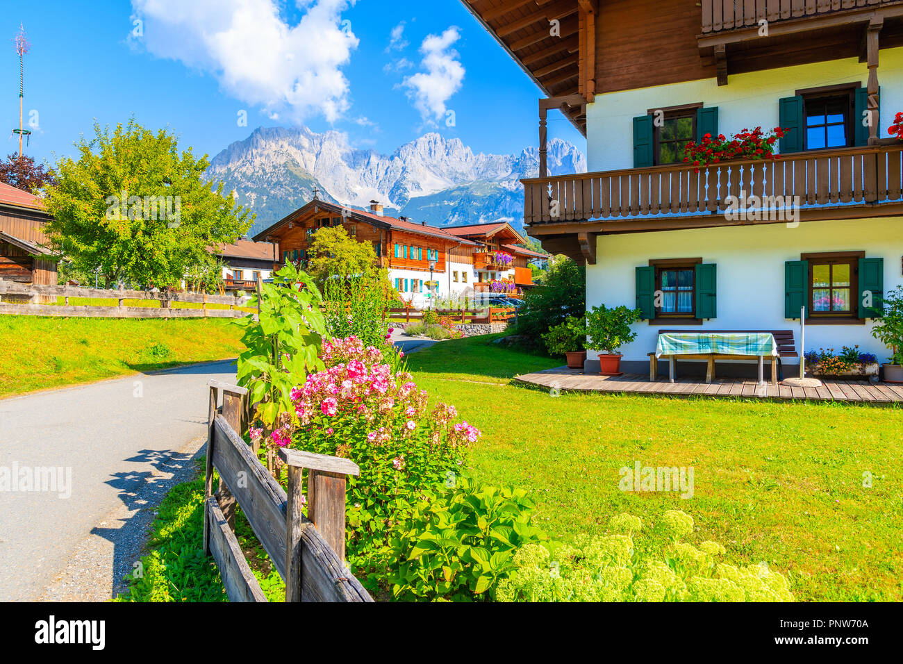 Tradizionale alpino in legno case decorate con fiori sul prato verde a Going am Wilden Kaiser villaggio montano su soleggiate giornate estive, Tirolo, Austria Foto Stock