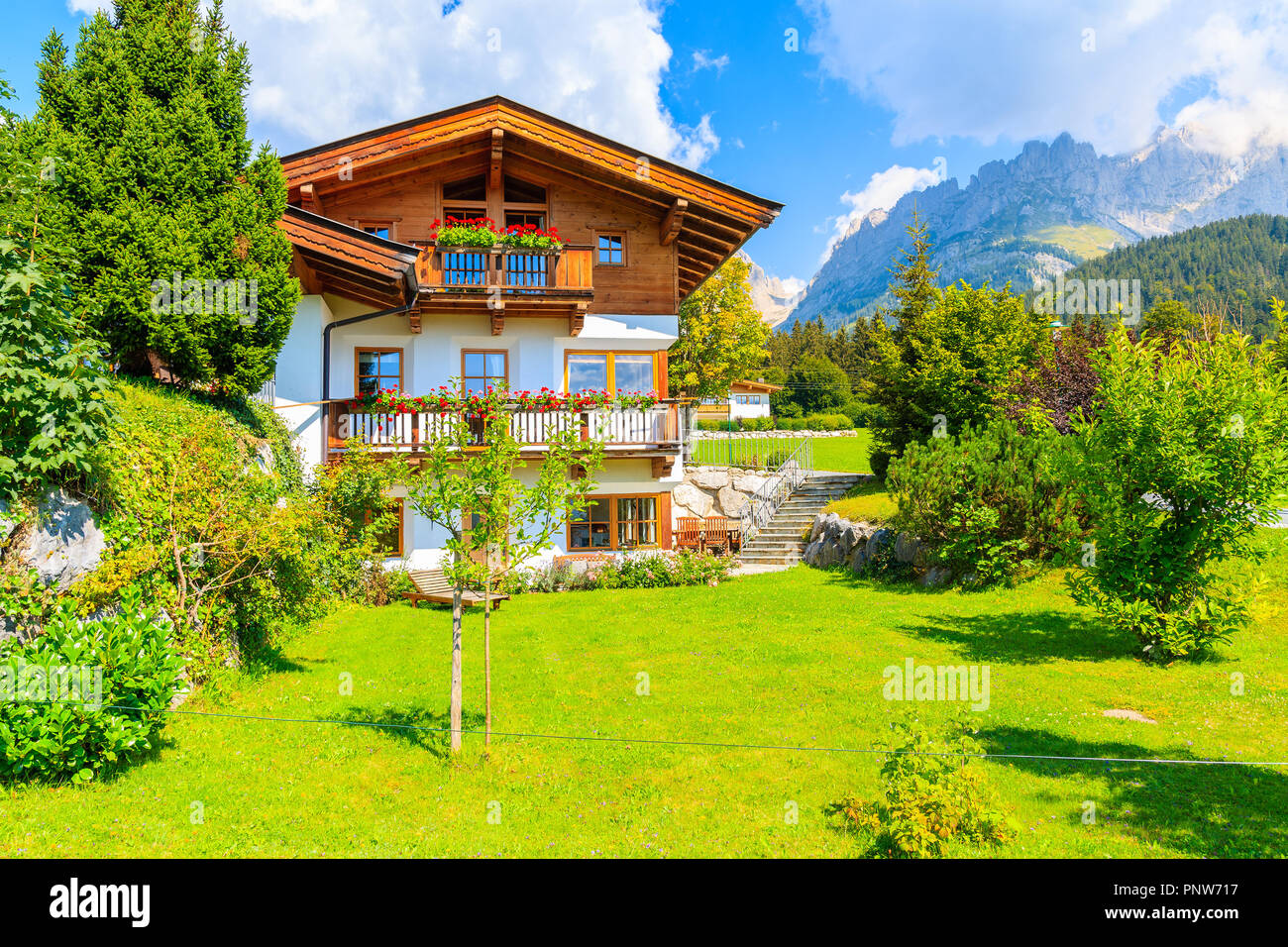 Tradizionale alpino in legno sul prato verde a Going am Wilden Kaiser villaggio montano su soleggiate giornate estive, Tirolo, Austria Foto Stock