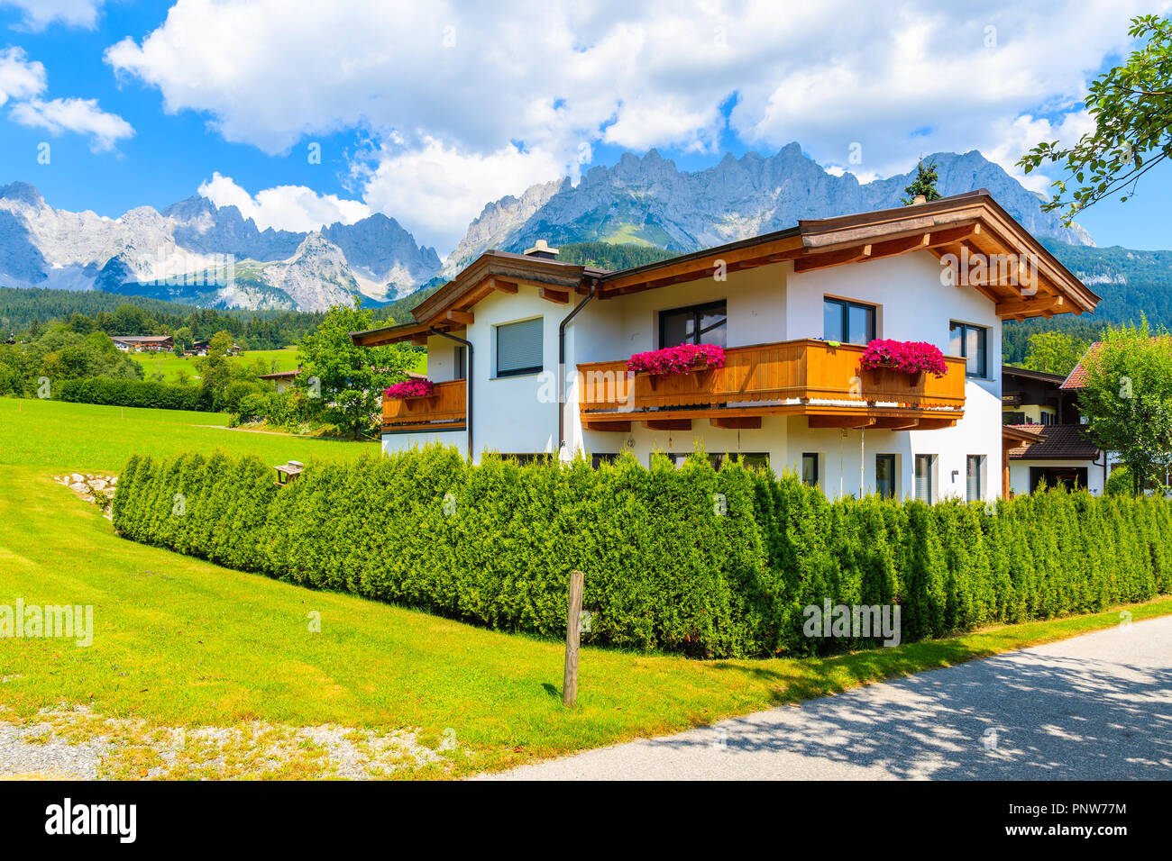 In legno tipico casa alpina decorate con fiori sul prato verde a Going am Wilden Kaiser villaggio sulla soleggiata giornata estiva, Tirolo, Austria Foto Stock