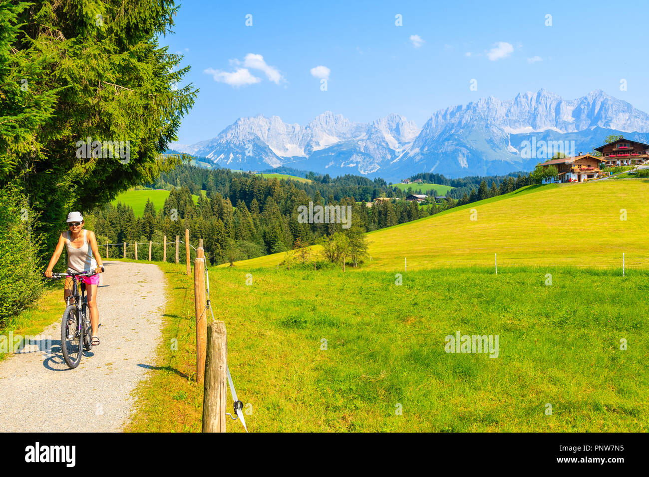 Giovane donna cicloturismo lungo il verde prato in Gieringer Weiher zona di montagna, Kitzbuhel Alpi, Austria Foto Stock