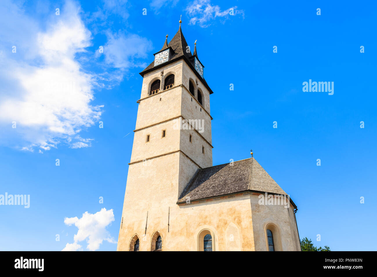 Campanile di una chiesa in Kitzbuhel cittadina soleggiata contro il cielo blu, Tirolo, Austria Foto Stock