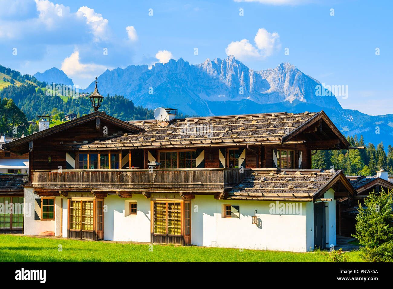 Tipica casa alpina sul prato verde in Reith bei Kitzbuhel villaggio nelle Alpi Montagne Paesaggio estivo sulla giornata di sole, Tirolo, Austria Foto Stock