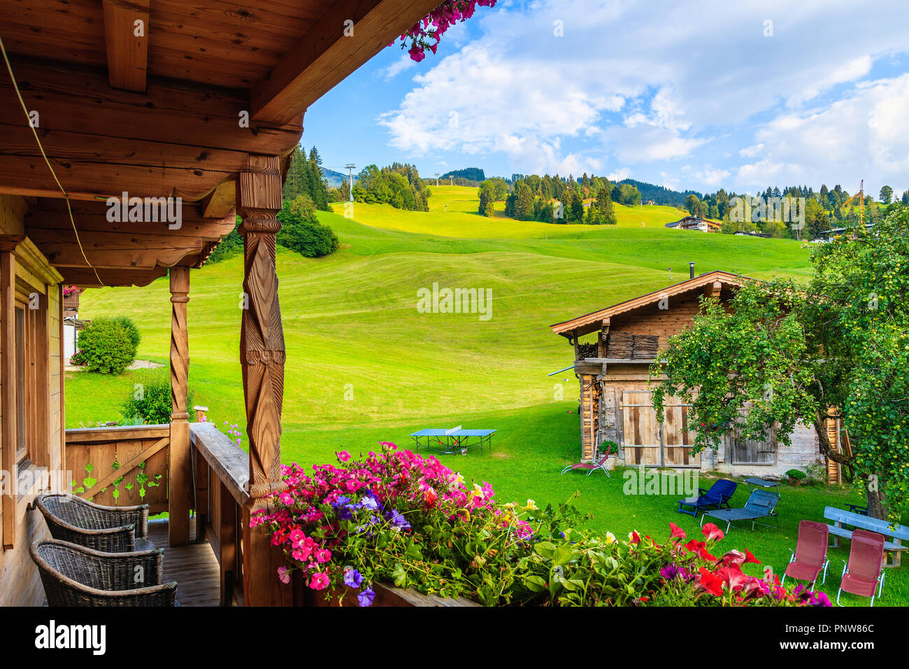 Vista del prato verde di montagne dalla tipica casa in legno balcone a Kirchberg villaggio sul giorno di estate, Alpi Kitzbühel, Austria Foto Stock