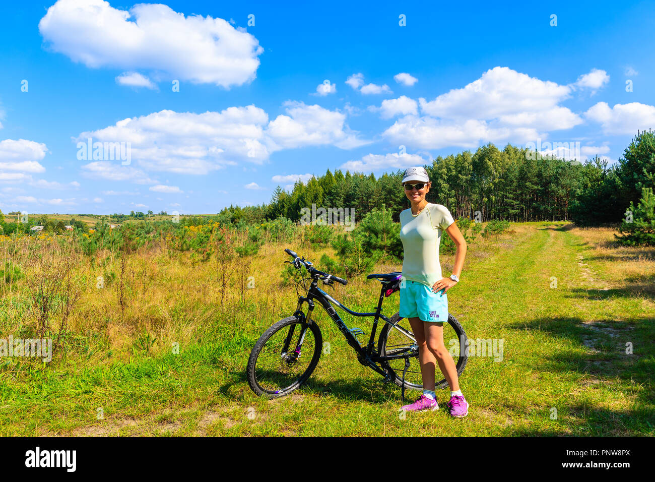 Pista ciclabile vicino OLKUSZ, Polonia - 9 Sep, 2018: giovane donna con la bicicletta e vista della foresta verde sulla soleggiata giornata estiva. Polonia meridionale ha molti attarente, Foto Stock