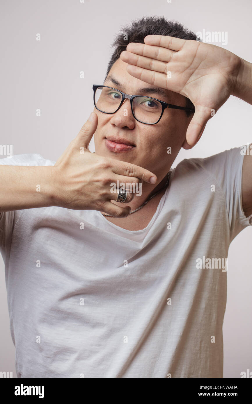 Funny Man coreano in occhiali e t-shirt mostra segno della fotocamera Foto Stock
