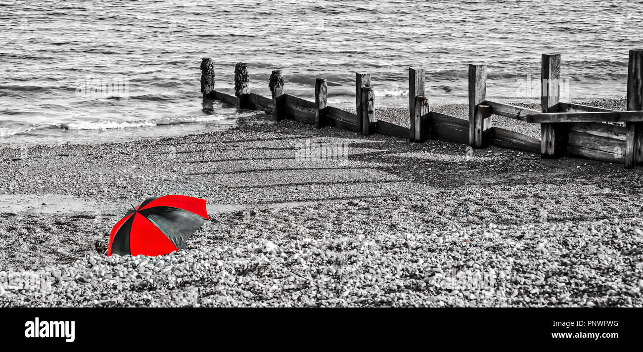 Vacanze in spiaggia il ricovero sotto un ombrello da un freddo vento Foto Stock