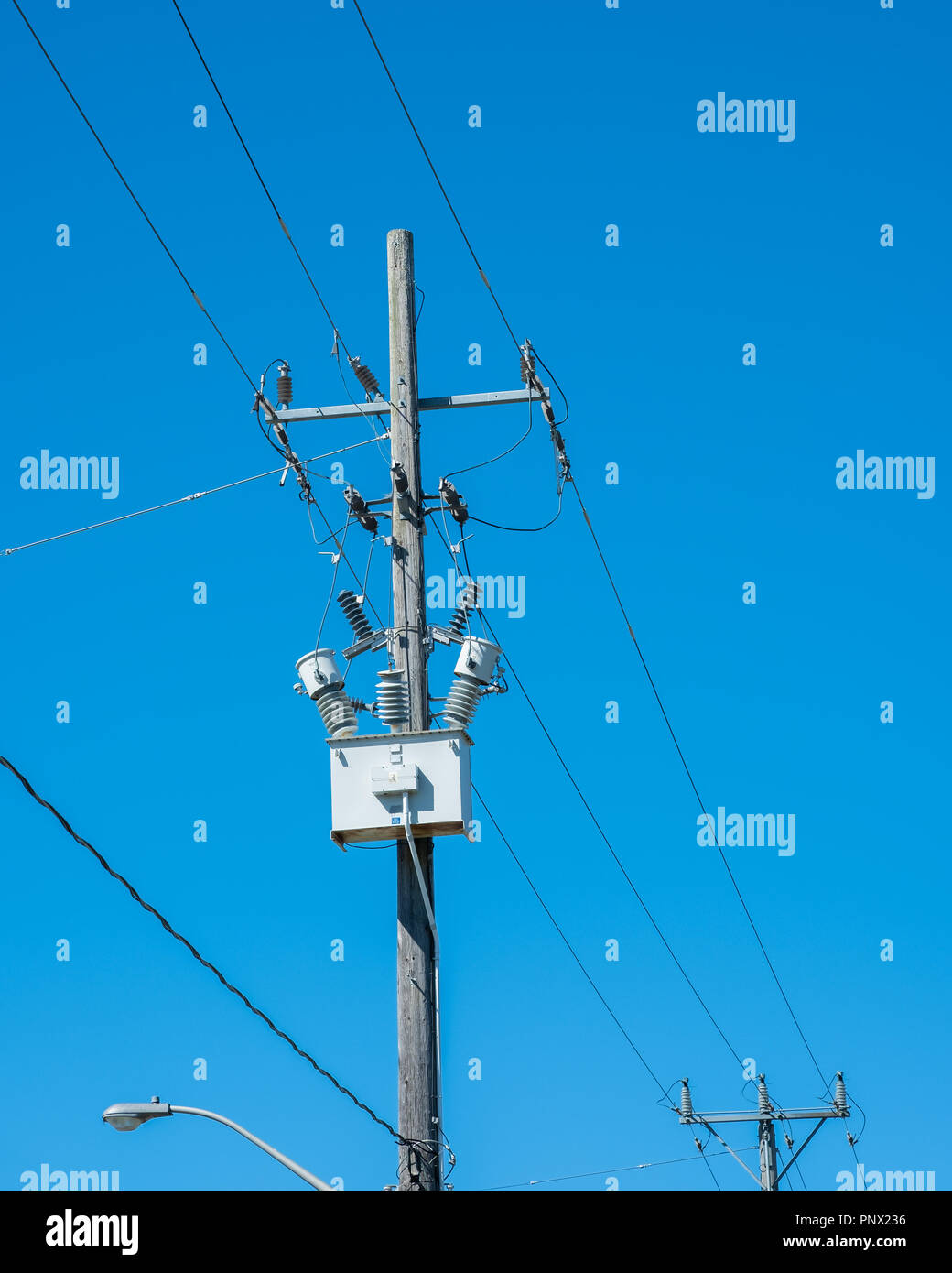 Fili alta tensione e una scatola trasformatore contro un chiaro i servizi essenziali, servizio, blu cielo con copia spazio. Foto Stock