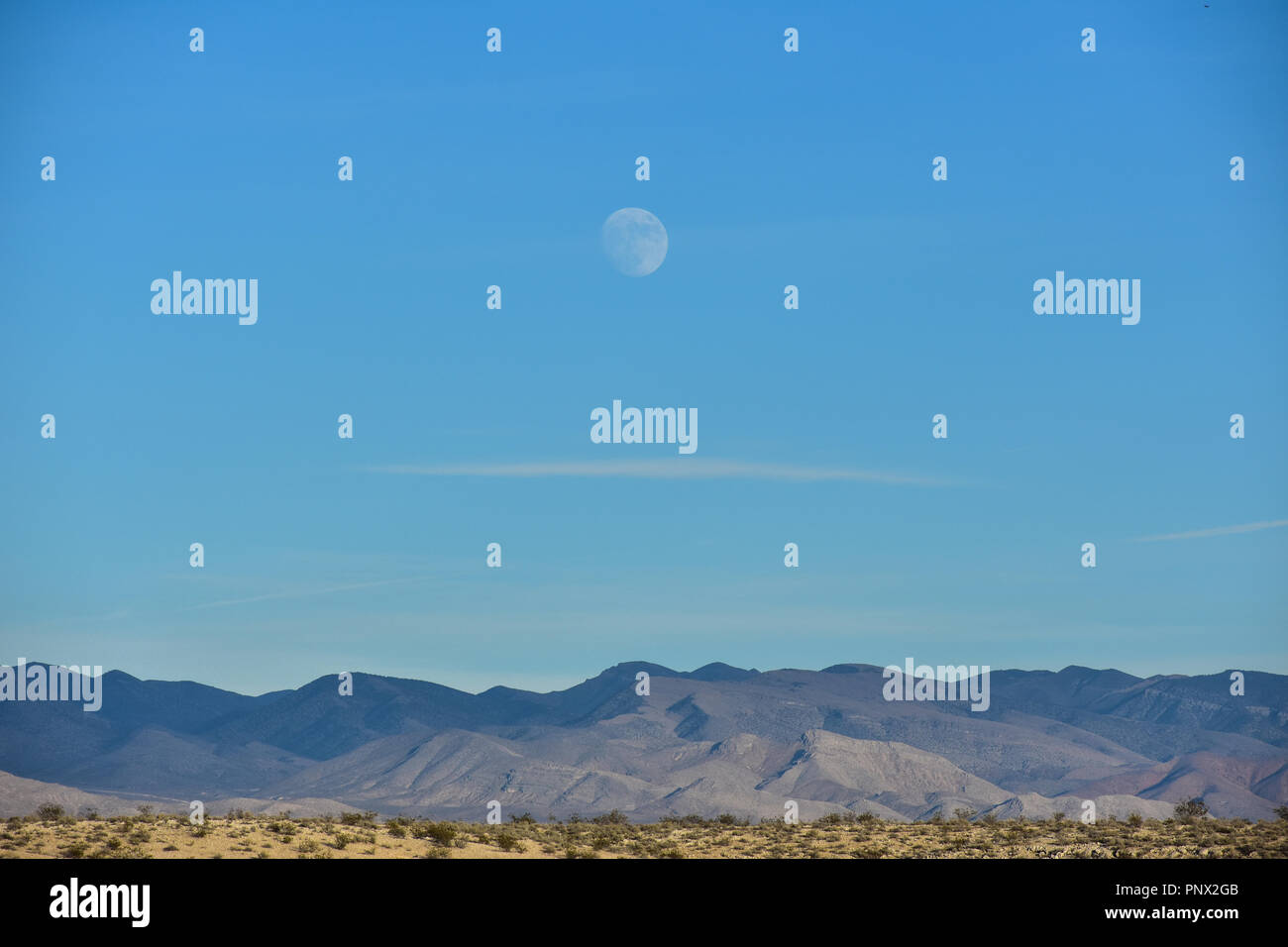Luna durante il giorno al di sopra delle montagne Foto Stock