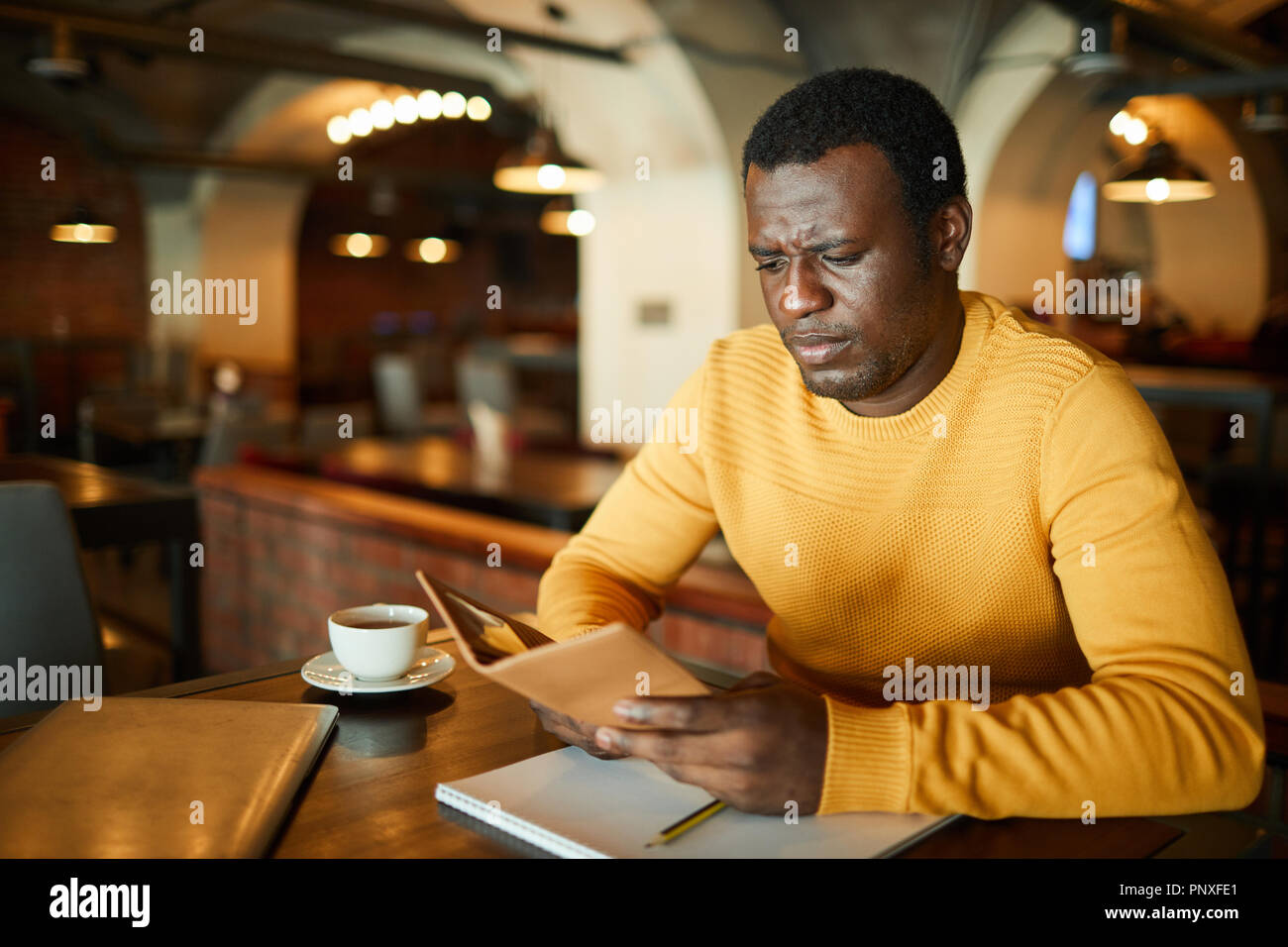 Client di giovani del ristorante moderno che esprimono incomprensioni o confusione mentre guardando bill con il prezzo del bere Foto Stock