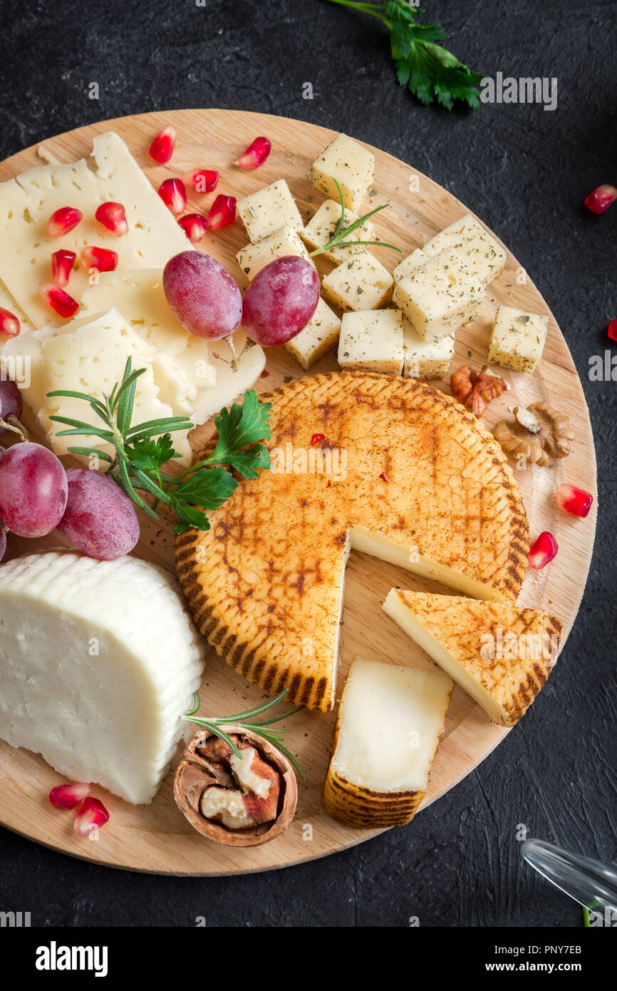 Un vassoio di formaggi con formaggi assortiti, uva, i dadi su sfondo nero, copia dello spazio. Formaggi italiani e piatti di frutta. Foto Stock