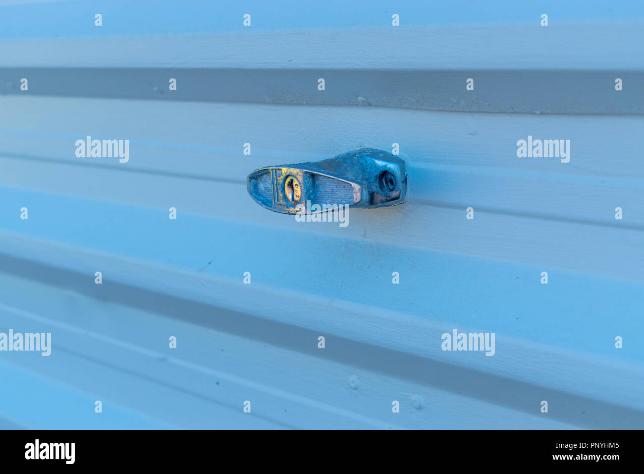 Colore bluastro tingono immagine di una maniglia porta per garage in posizione bloccata su una luce colorata metallo scanalato otturatore Foto Stock