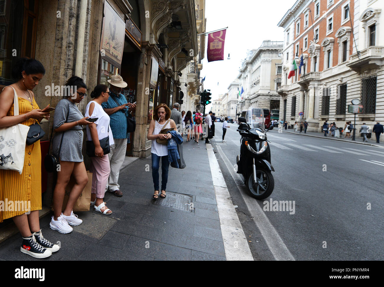 Le donne italiane utilizzando il loro smartphone sulla Via Del Corso nel centro di Roma. Foto Stock