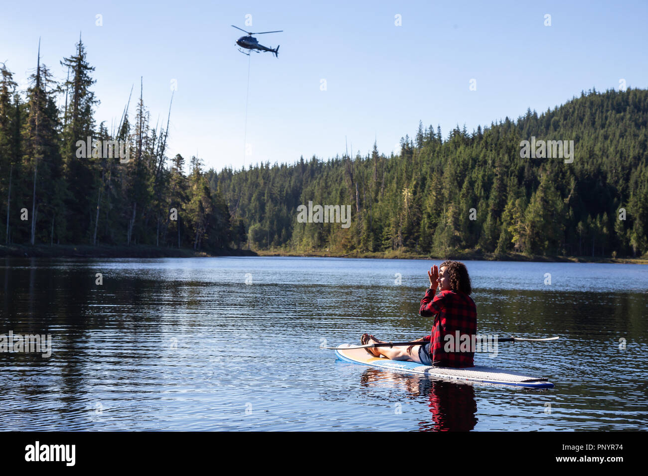 Nord di Isola di Vancouver, British Columbia, Canada - Agosto 17, 2018: Ragazza su un dispositivo di compressione scheda è la visione di un elicottero di combattimento selvaggio BC gli incendi boschivi. Foto Stock