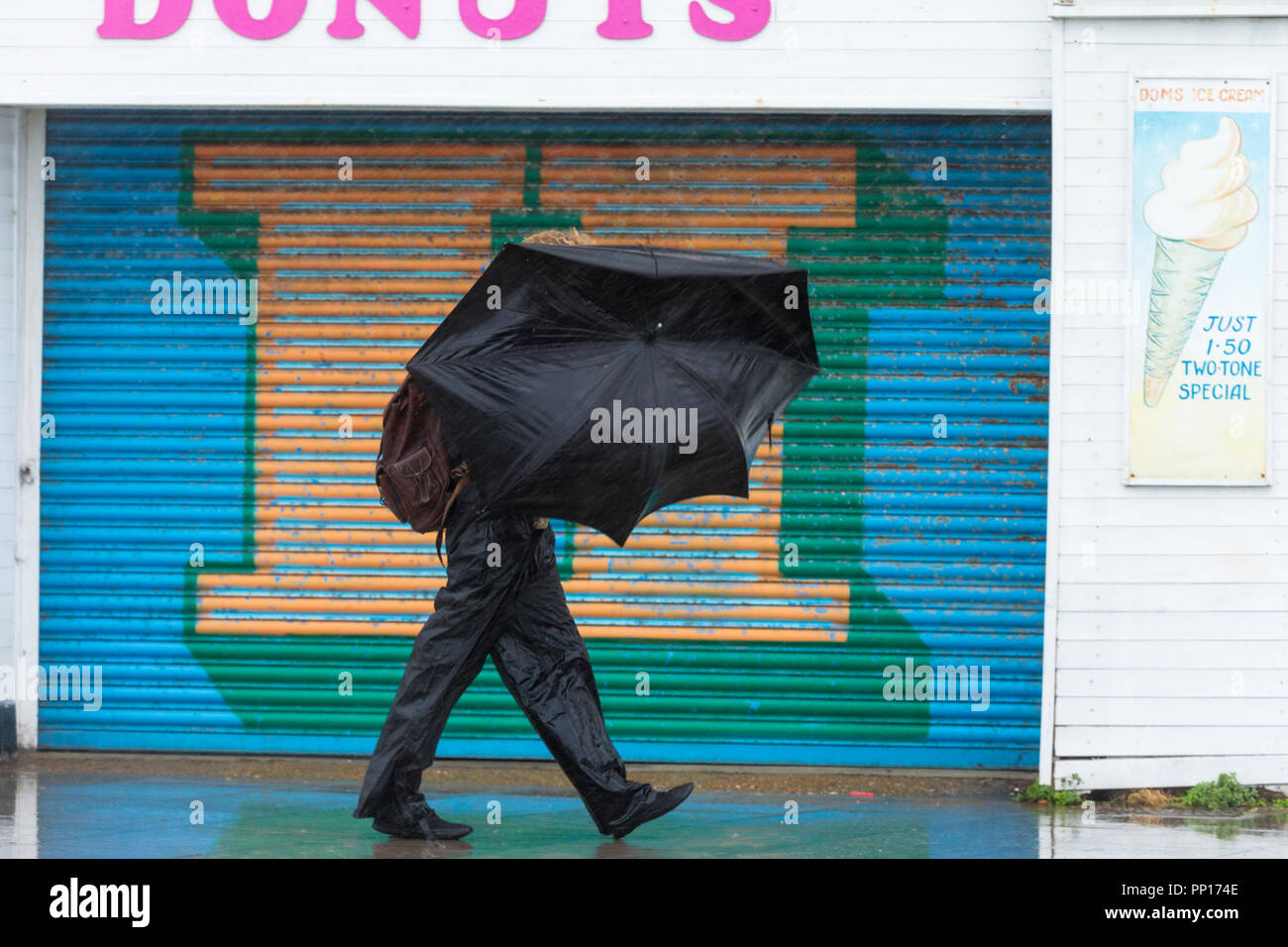 Hastings, East Sussex, Regno Unito. 23rd Set 2018. UK Meteo: Pioggia intensa e vento guida nella città balneare di Hastings questa mattina, le temperature sono scese sotto i 13°C. Quest'uomo perde quasi il suo ombrello mentre una raffica di vento lo trasforma dentro fuori. Photo Credit: Paul Lawrenson / Alamy Live News Foto Stock