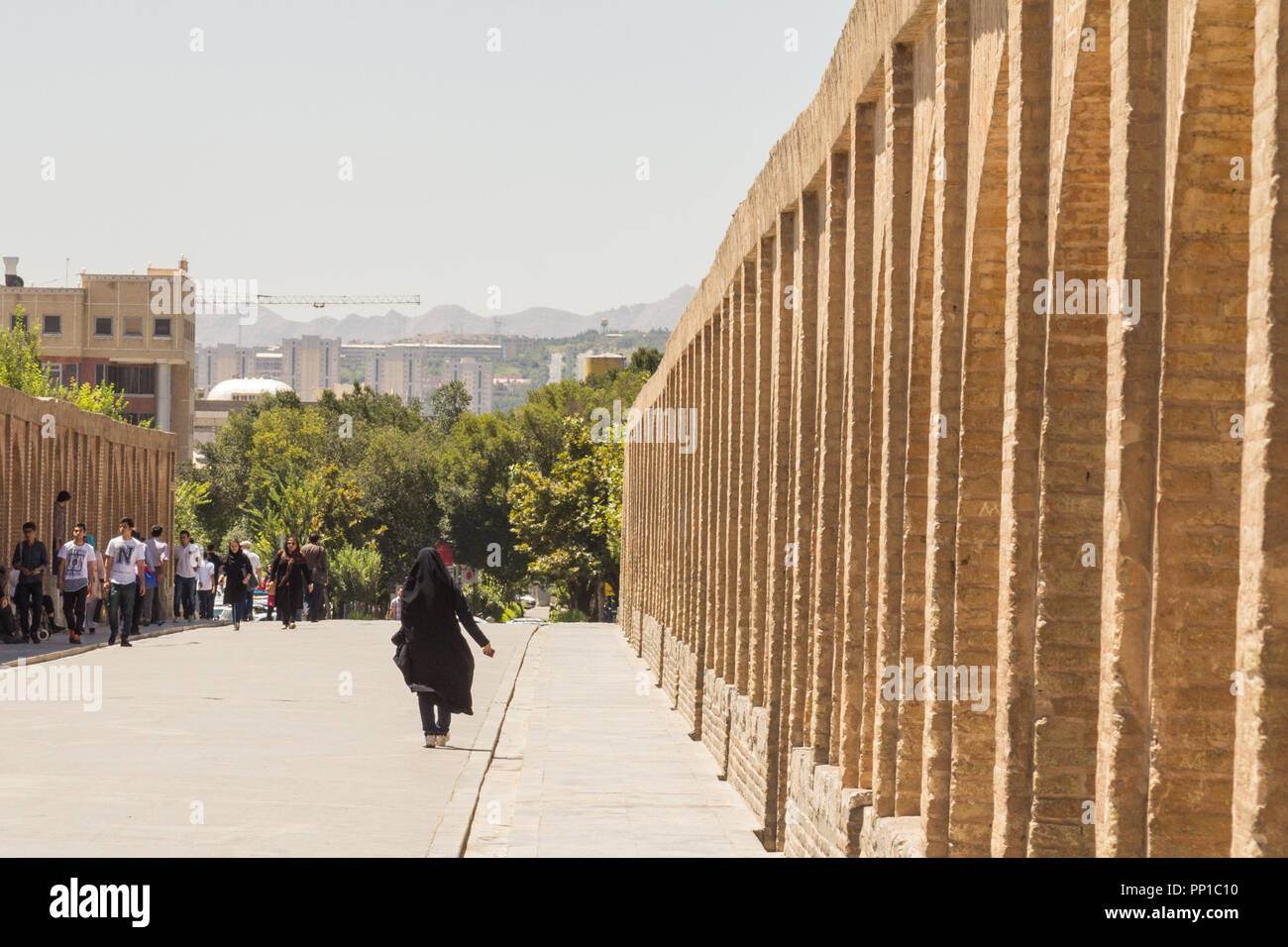 ISFAHAN, IRAN - Agosto 7, 2015: donna iraniana che indossa il musulmano tradizionale velo nero camminano su Si o Seh Pol ponte. Noto anche come Allahverdi Khan B Foto Stock