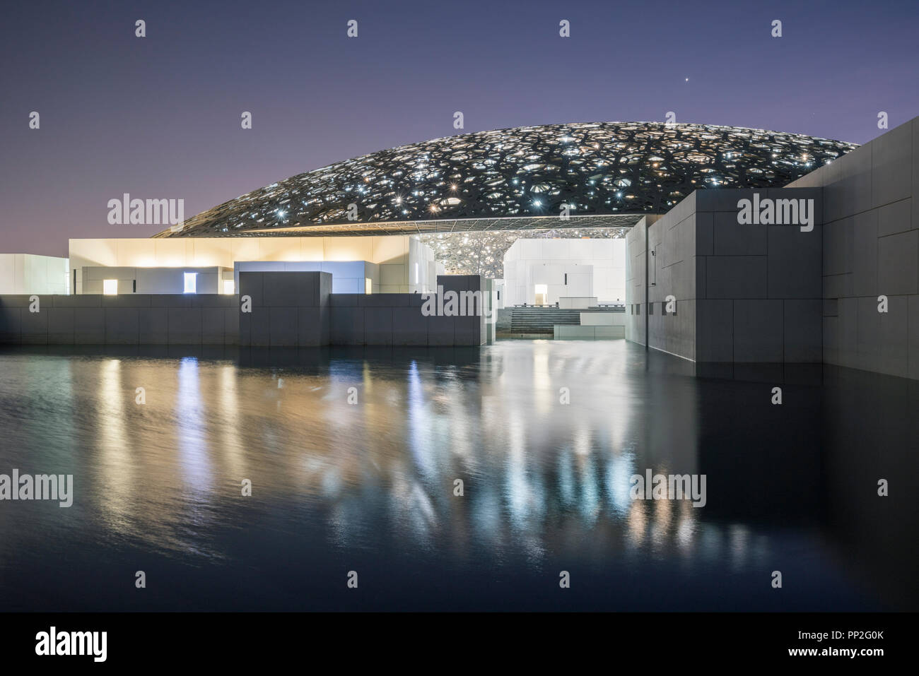 Esterno vista serale del Louvre Abu Dhabi a Saadiyat isola il distretto culturale di Abu Dhabi, negli Emirati Arabi Uniti. Architetto Jean Nouvel Foto Stock