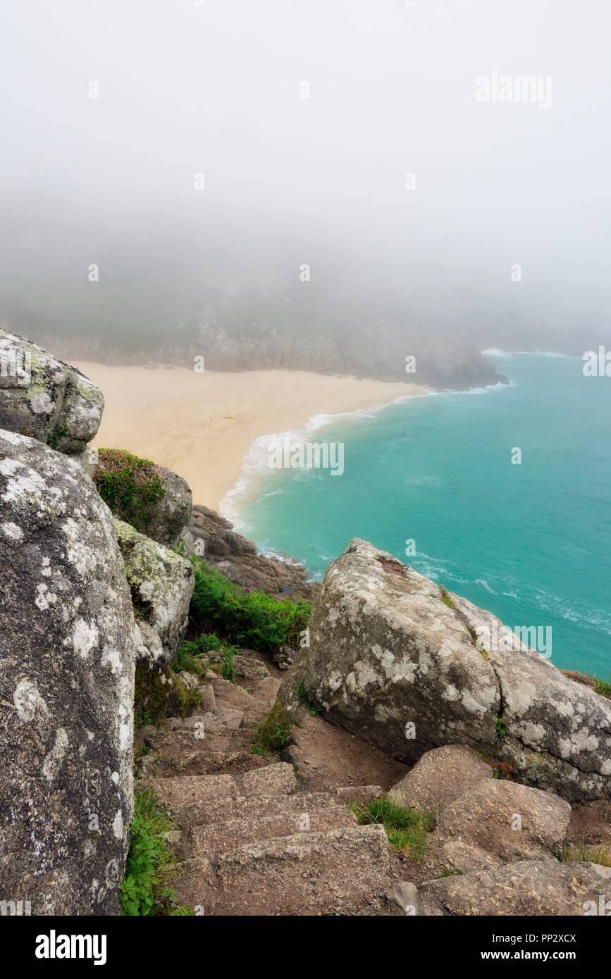 Guardando verso il basso sulla spiaggia Porthcurno in una nebbiosa mattina di Cornovaglia,Cornwall,l'Inghilterra,UK Foto Stock