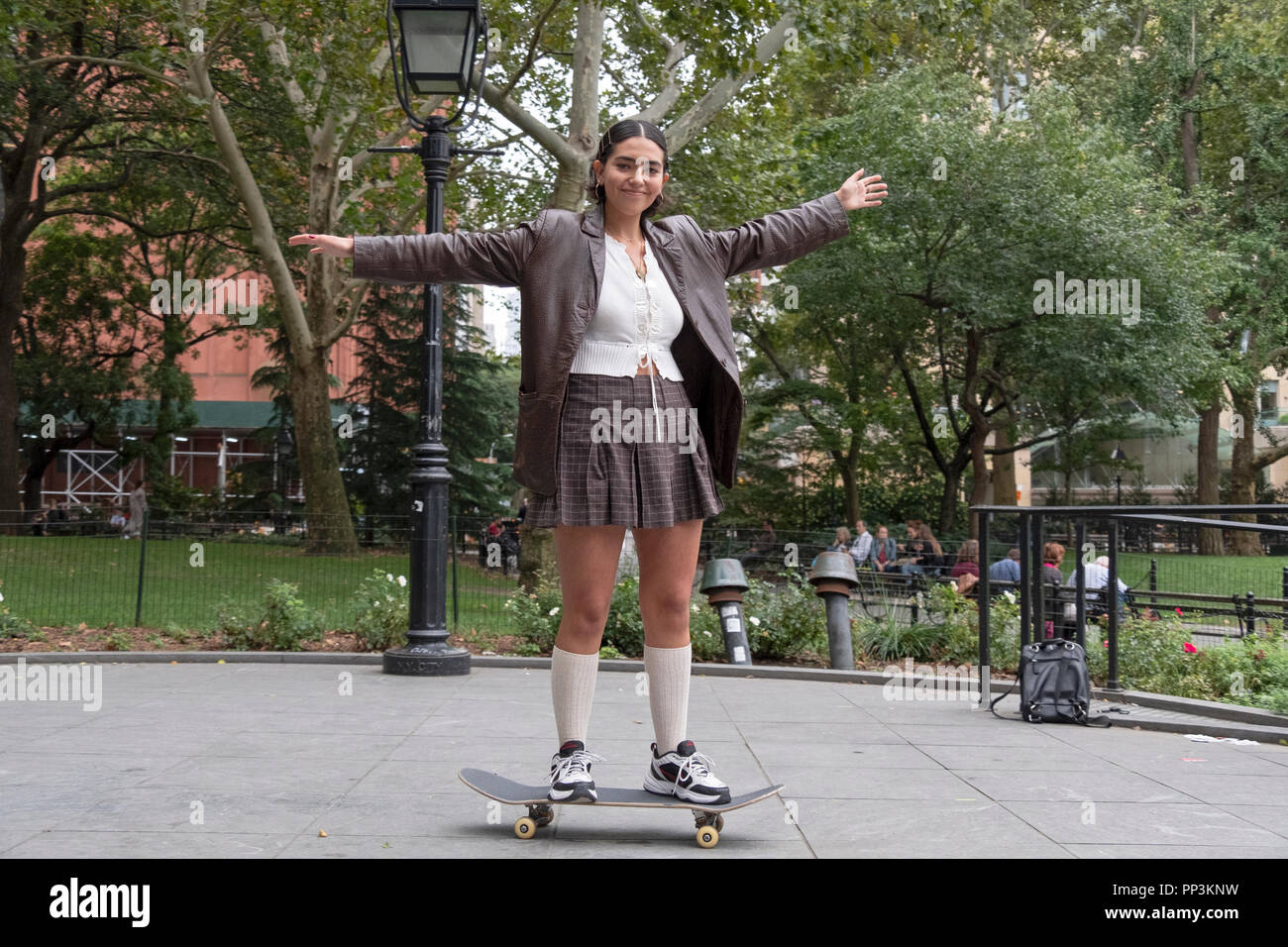 Foto di un attraente ragazza a cavallo su uno skateboard in Washington Square Park di New York City. Foto Stock