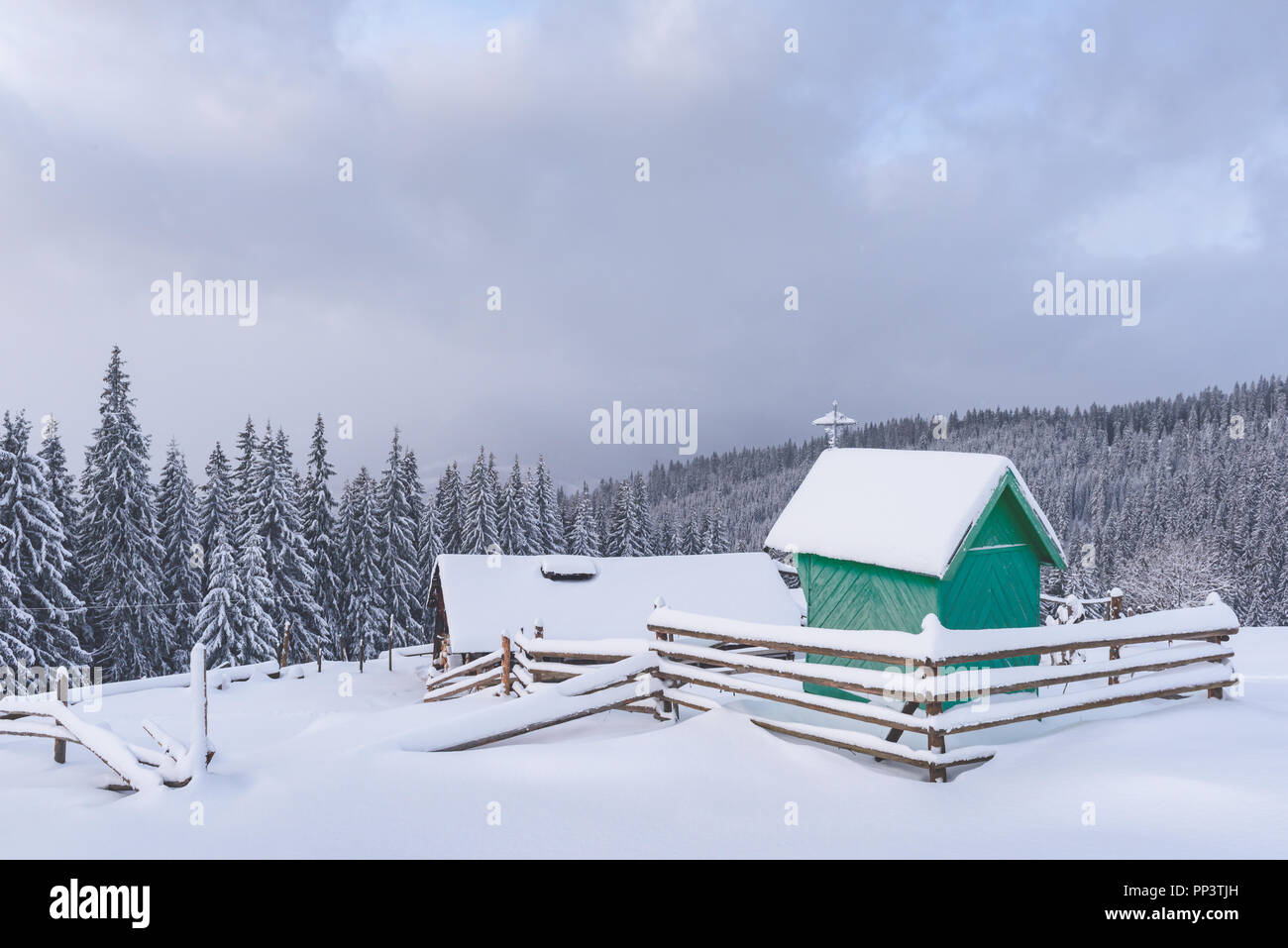 Fantastico paesaggio invernale con verde cappella in legno e casa in montagna innevata. Vacanze di Natale concetto. Carpazi montagna, Ucraina, Europa Foto Stock