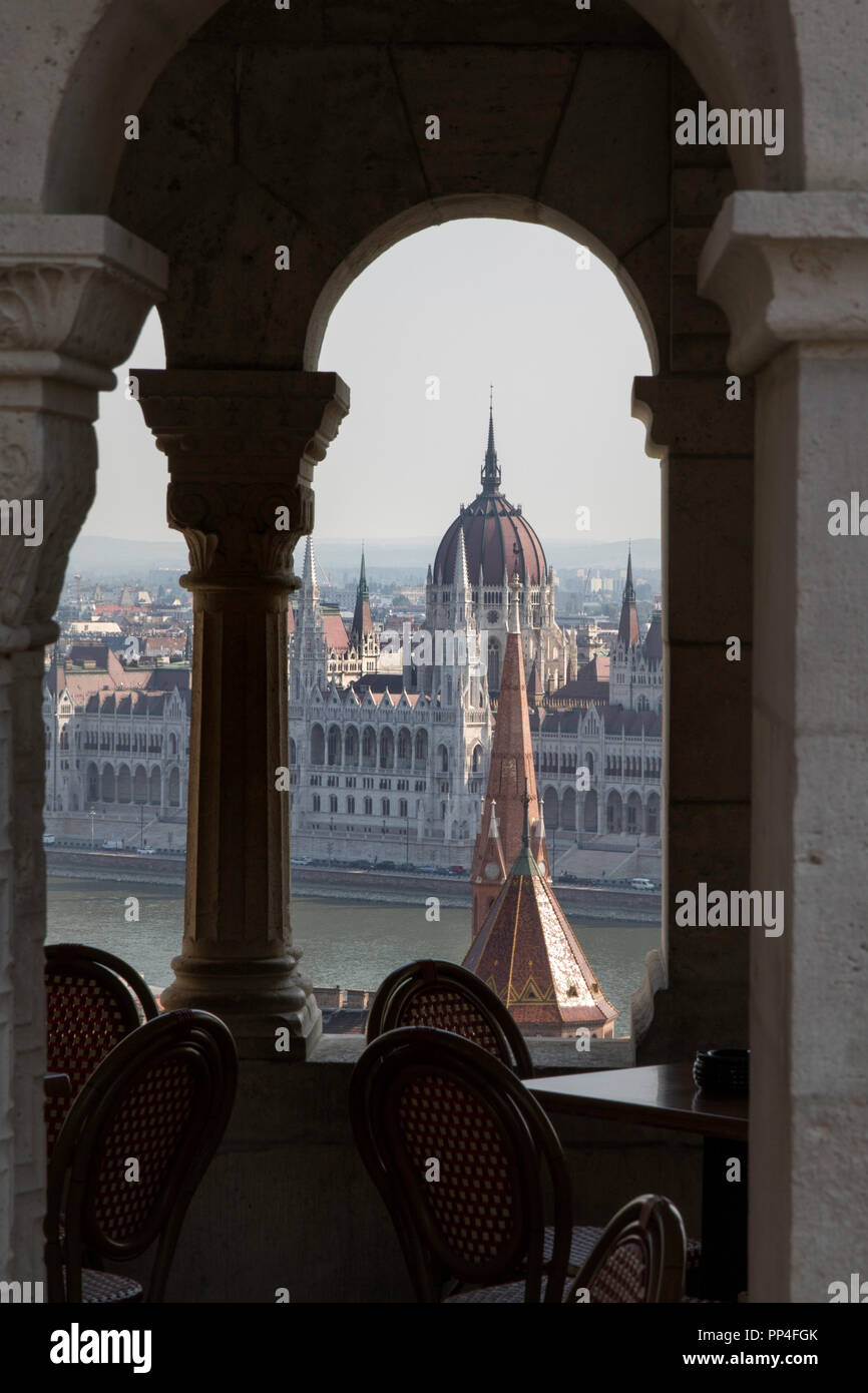 Il Parlamento ungherese palazzo visto attraverso gli archi del bastione dei pescatori a Budapest's Castle Hill Foto Stock