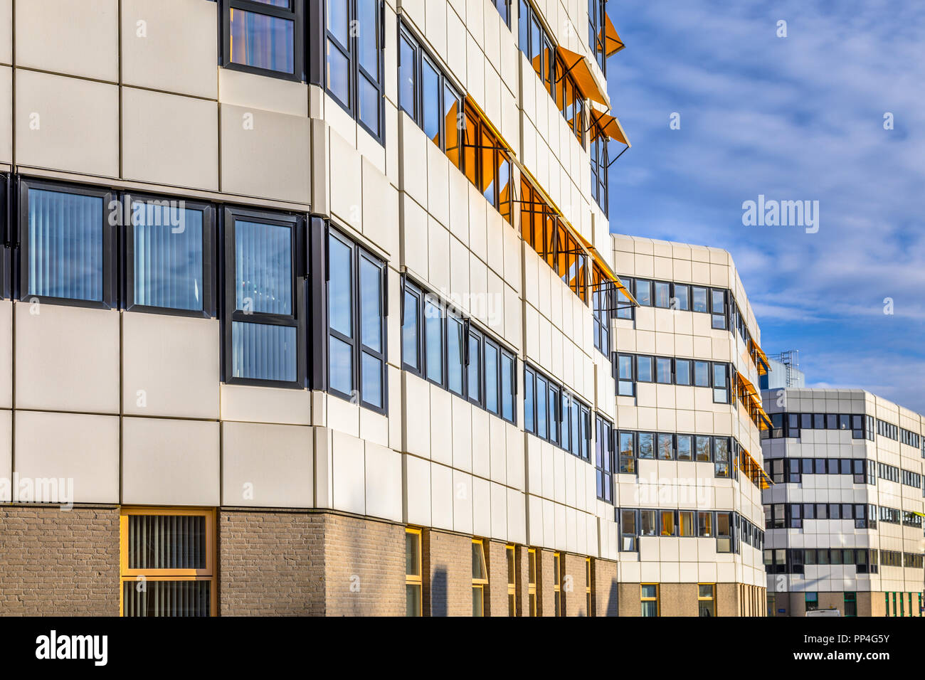 Classico bianco e nero edifici ospedalieri su una riga sotto il cielo blu con nuvole alte Foto Stock
