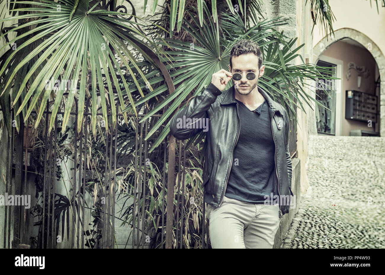 Attraente uomo all' aperto nel vecchio castello europeo, in Svizzera. Athletic build, con maglietta stretta e occhiali da sole Foto Stock