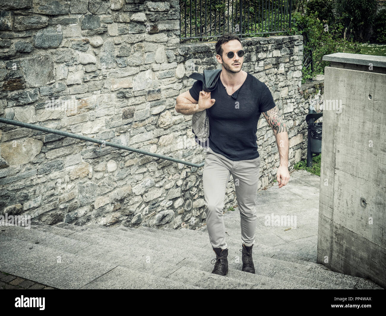 Attraente uomo all' aperto nel vecchio castello europeo, in Svizzera. Athletic build, con maglietta stretta e occhiali da sole Foto Stock