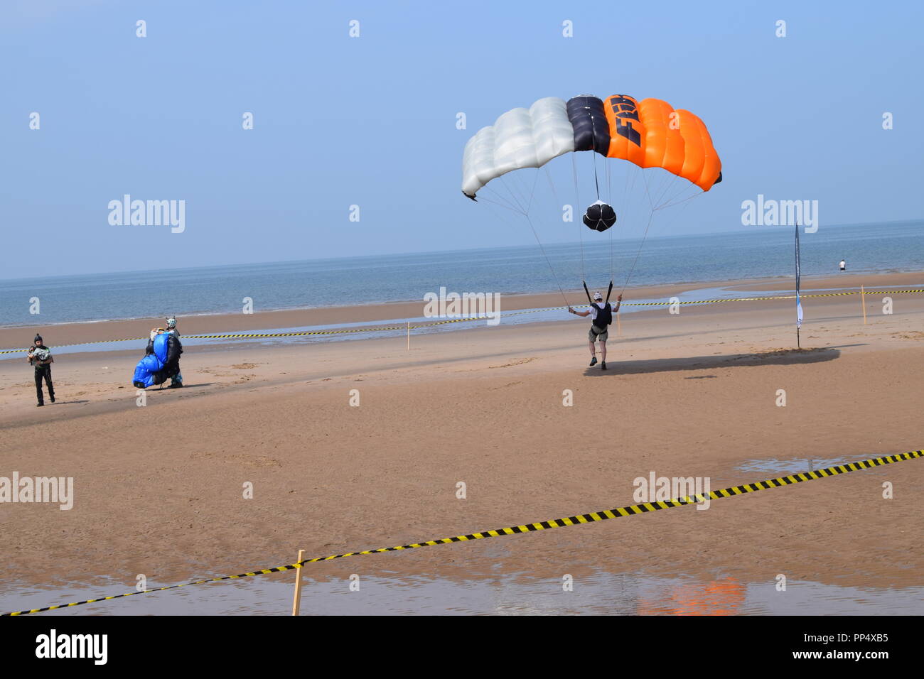 Una base jumping evento sulla spiaggia di Blackpool Inghilterra uk atterraggio con il paracadute sulla spiaggia di sabbia fine e dorata. Un bel blu del cielo e del mare Foto Stock