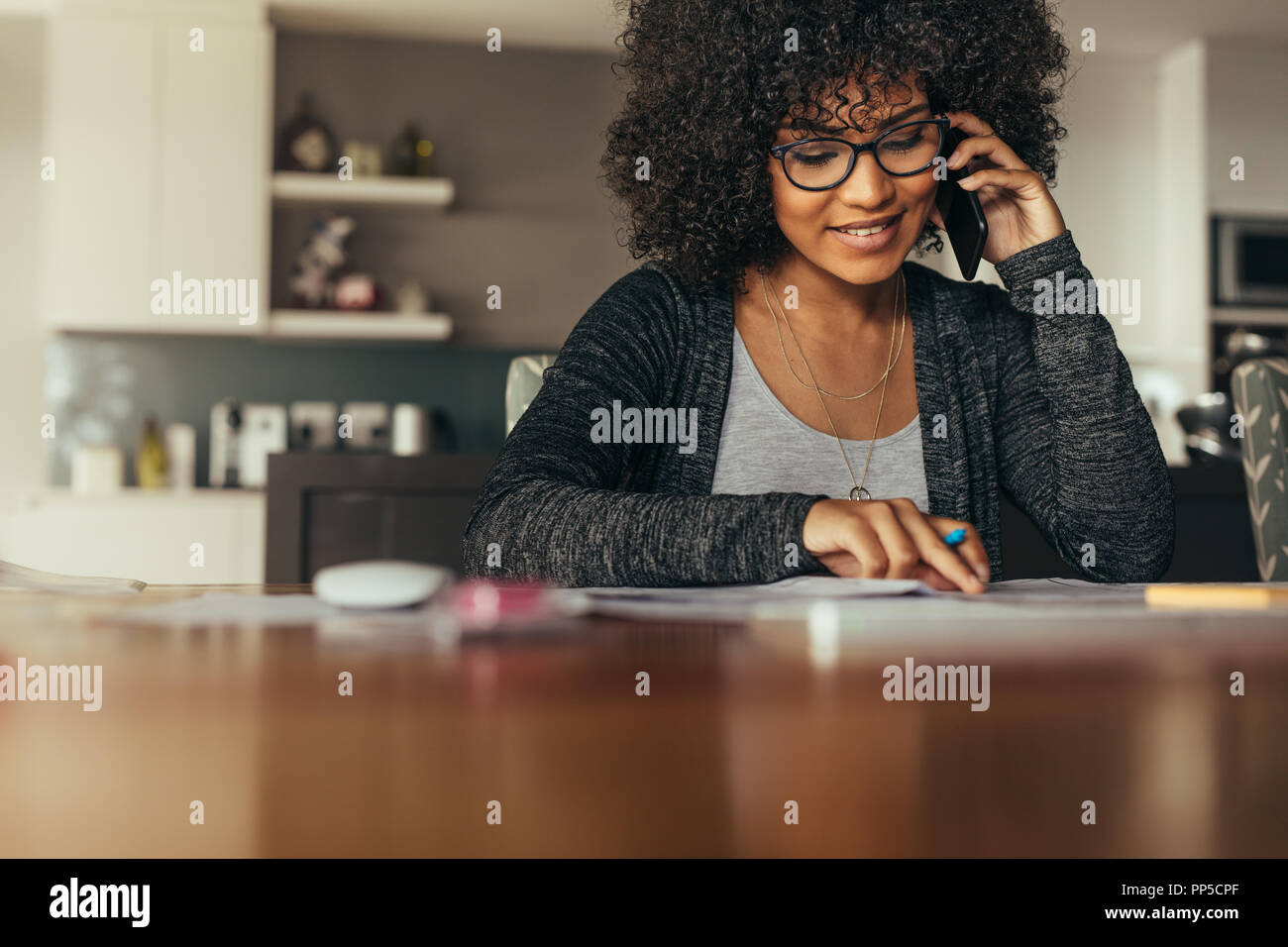 Ritratto di felice giovane femmina interior designer guardando il disegno e più di parlare di smart phone. Giovane architetto usando il telefono al suo posto di lavoro. Foto Stock