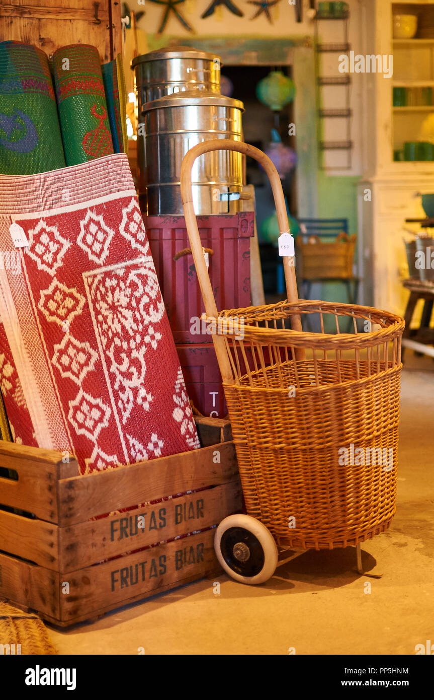 Tappeti, frutta case di legno, bidoni di metallo, reed carrello per la vendita in Can Xicu negozio vintage a El Pilar de La Mola (La Mola, Formentera, isole Baleari, Spagna) Foto Stock