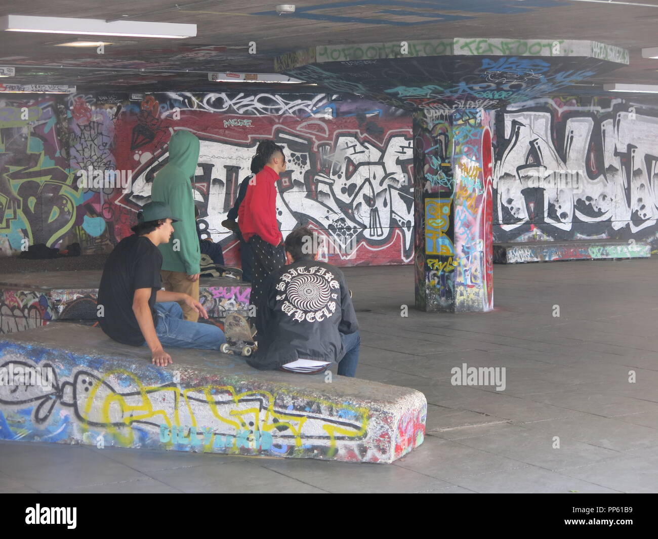 Un gruppo di giovani con i loro skateboard "appendere fuori' in un molto-graffitied sottopassaggio sulla London South Bank. Foto Stock