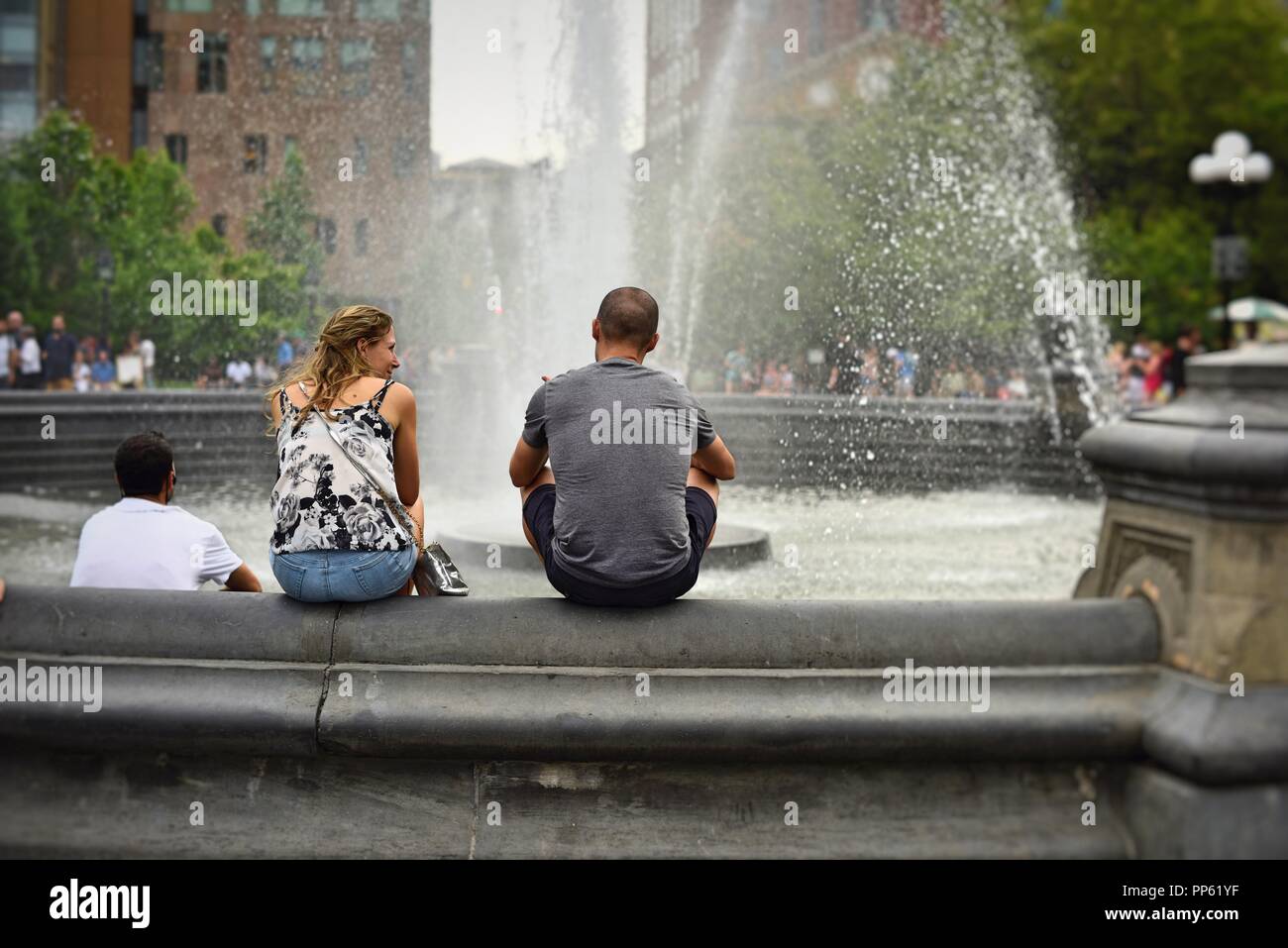 New York, NY; Giugno 2017: un giovane si siede insieme presso la fontana di Washington Square Park Foto Stock