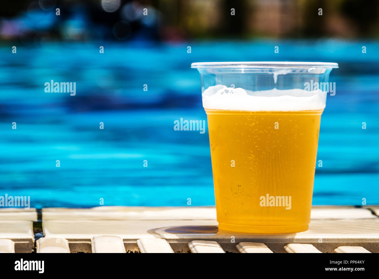 Bottiglia in plastica con birra alla spina nella giornata di sole in estate vicino alla piscina Foto Stock