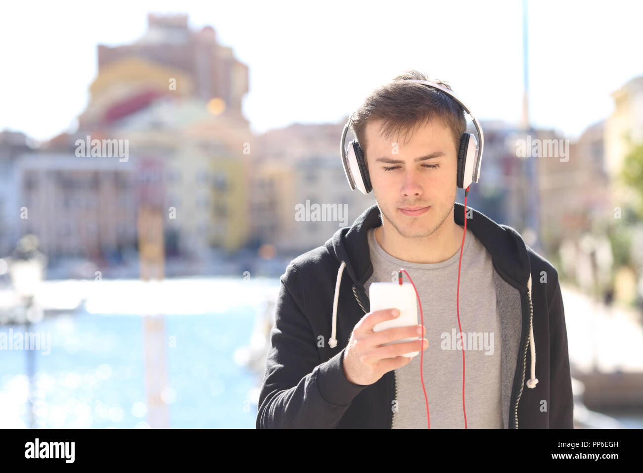 Vista Fronf ritratto di un grave teen ascoltando la musica di strada di una città costiera Foto Stock