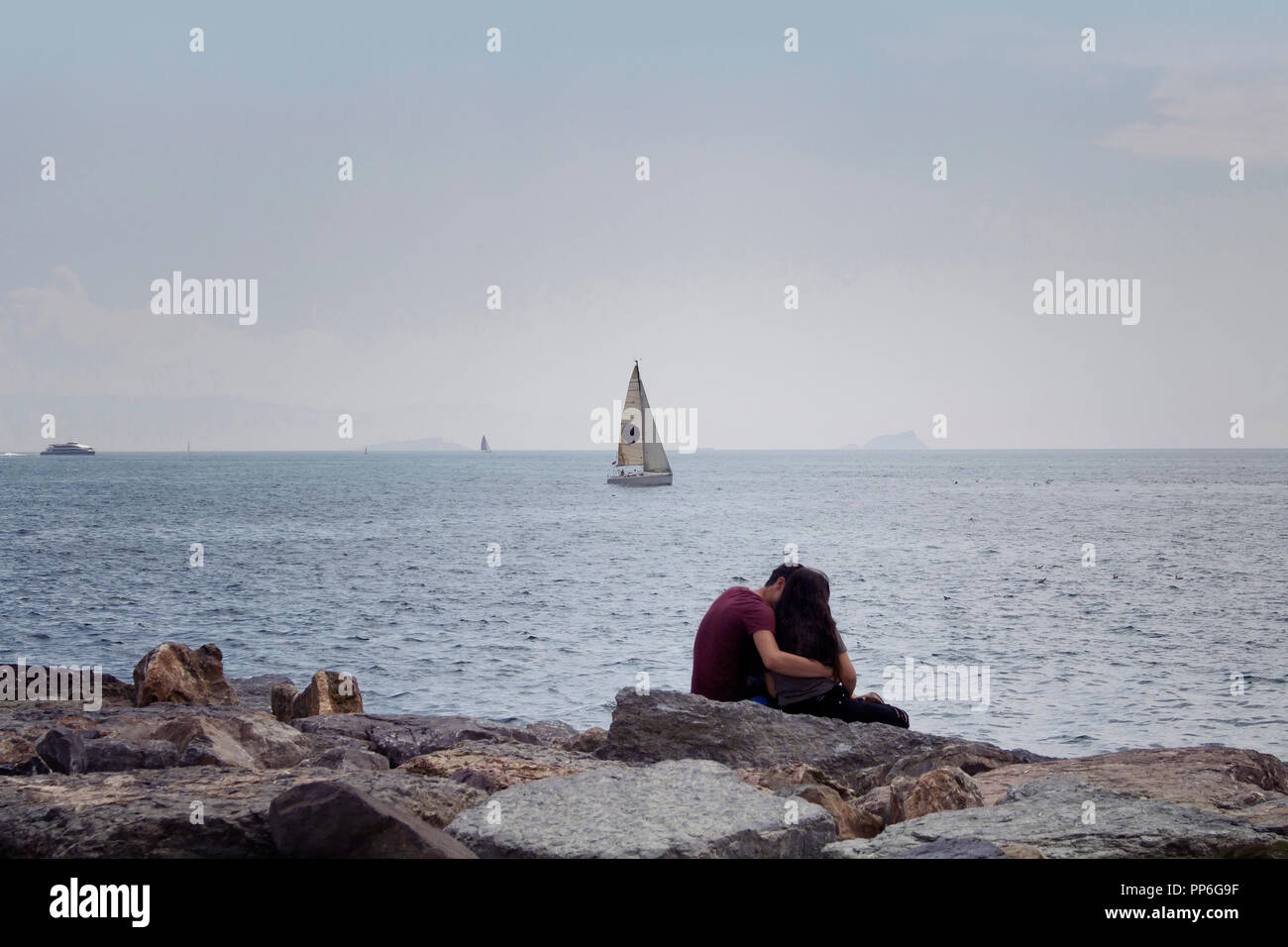Vista di un irriconoscibile coppia giovane seduto sulle rocce dal Bosforo. Immagine è catturata nel quartiere chiamato Moda situato sul lato Asiatico Foto Stock