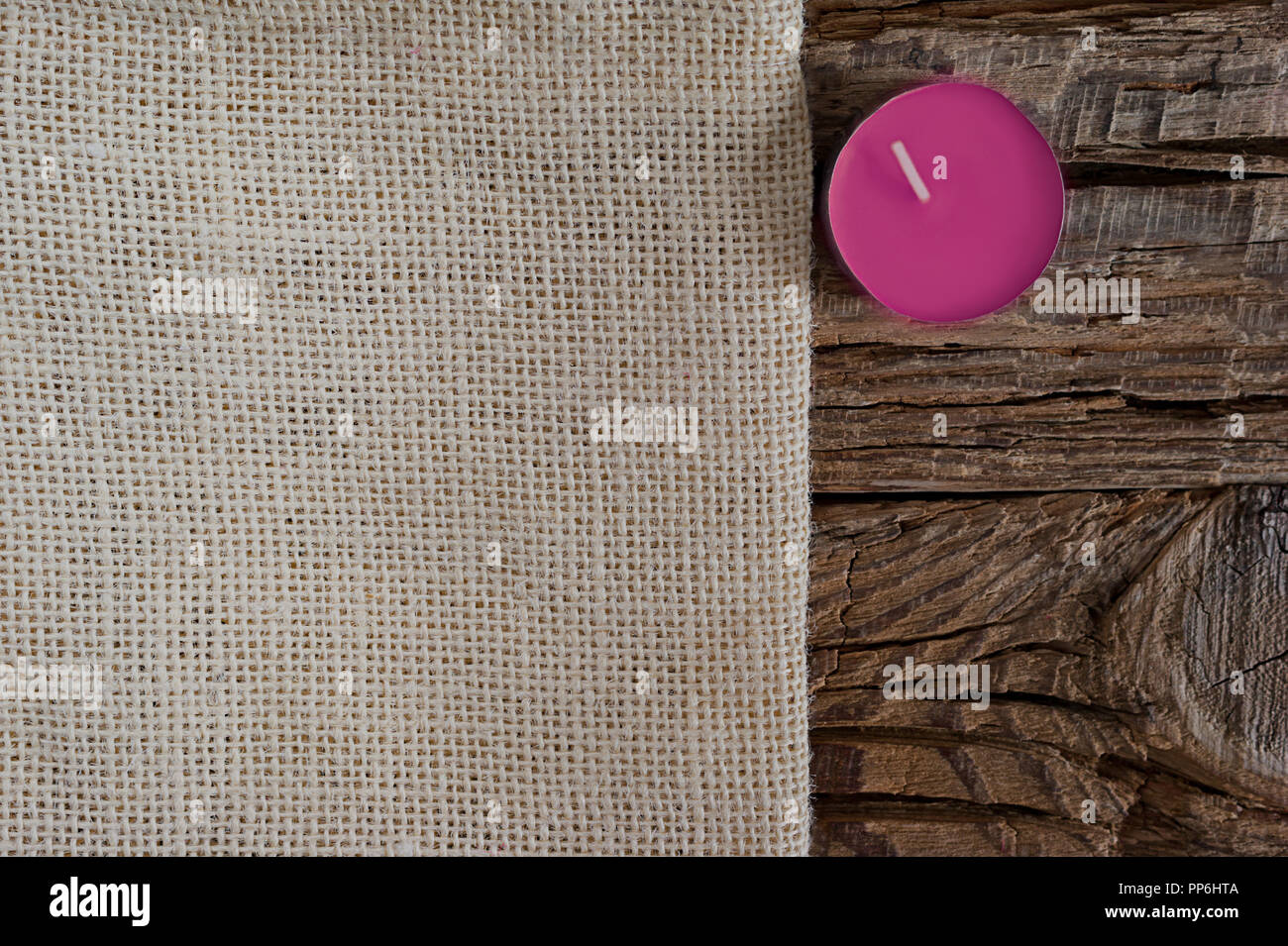 Stagione di biglietto di auguri concetto di design con copia spazio. Panno Beige su una grossa sullo sfondo di legno con un'orchidea viola candela. Foto Stock